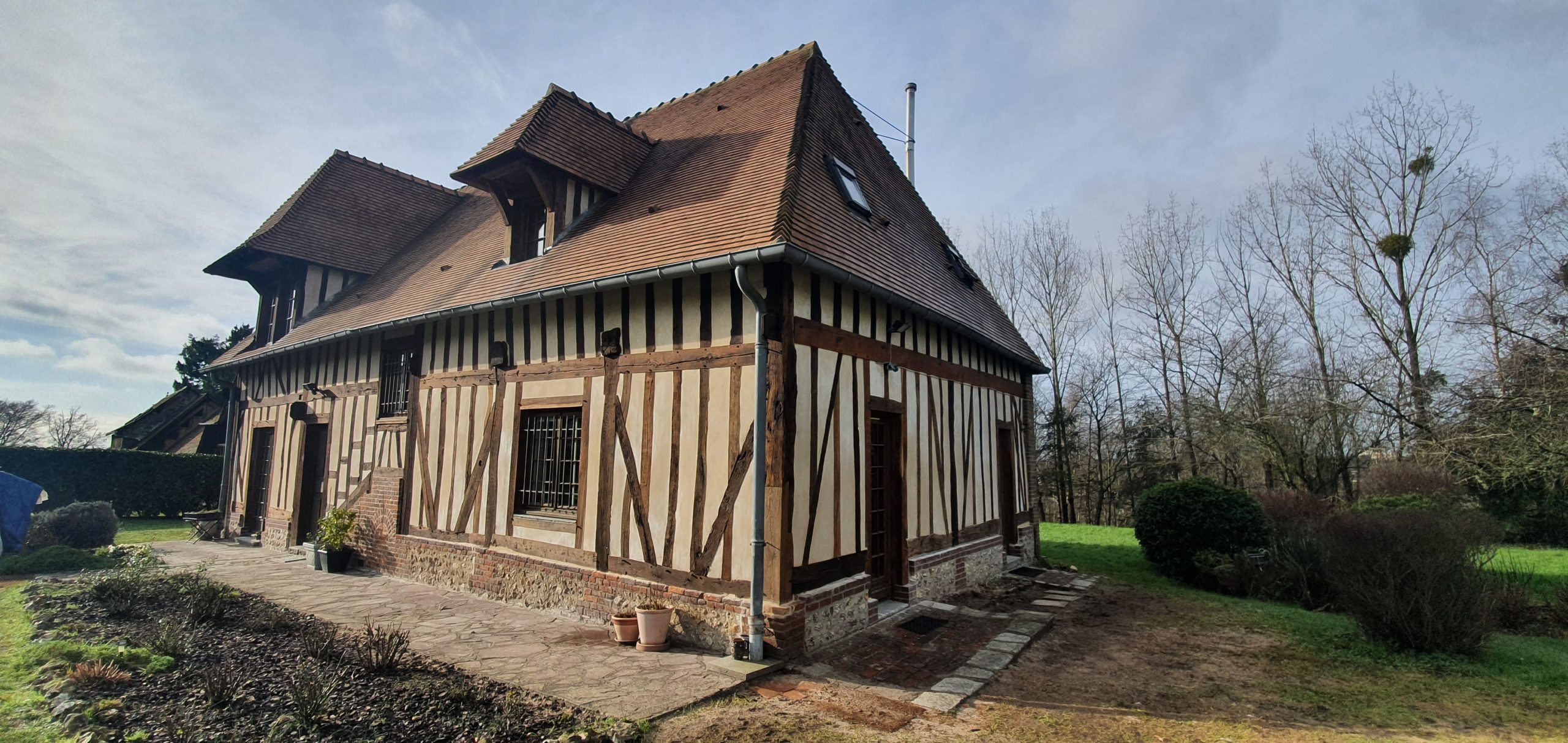 Charpente, colombages, enduits à la chaux, maçonnerie de briques et silex.