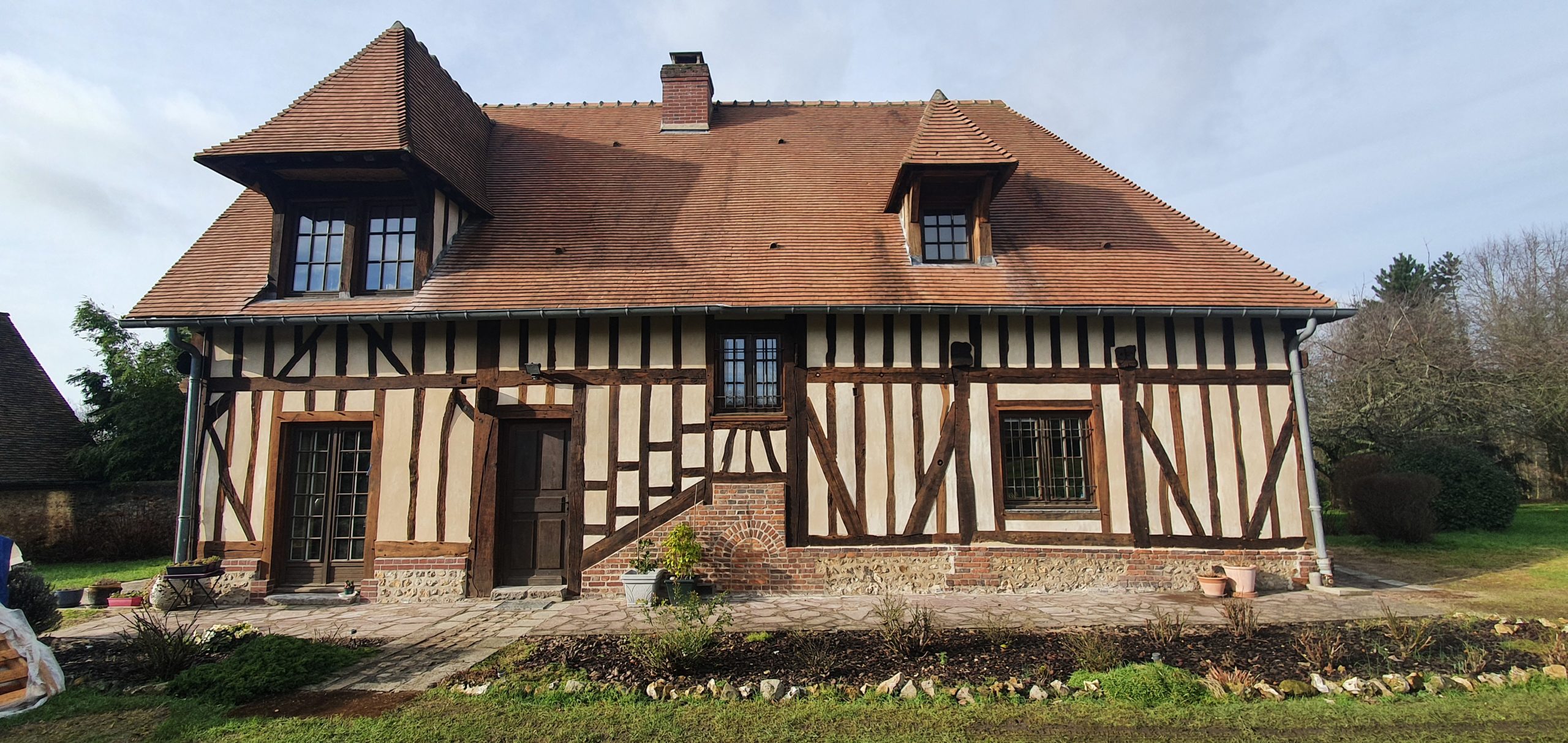 Charpente, colombages, enduits à la chaux, maçonnerie de briques et silex.