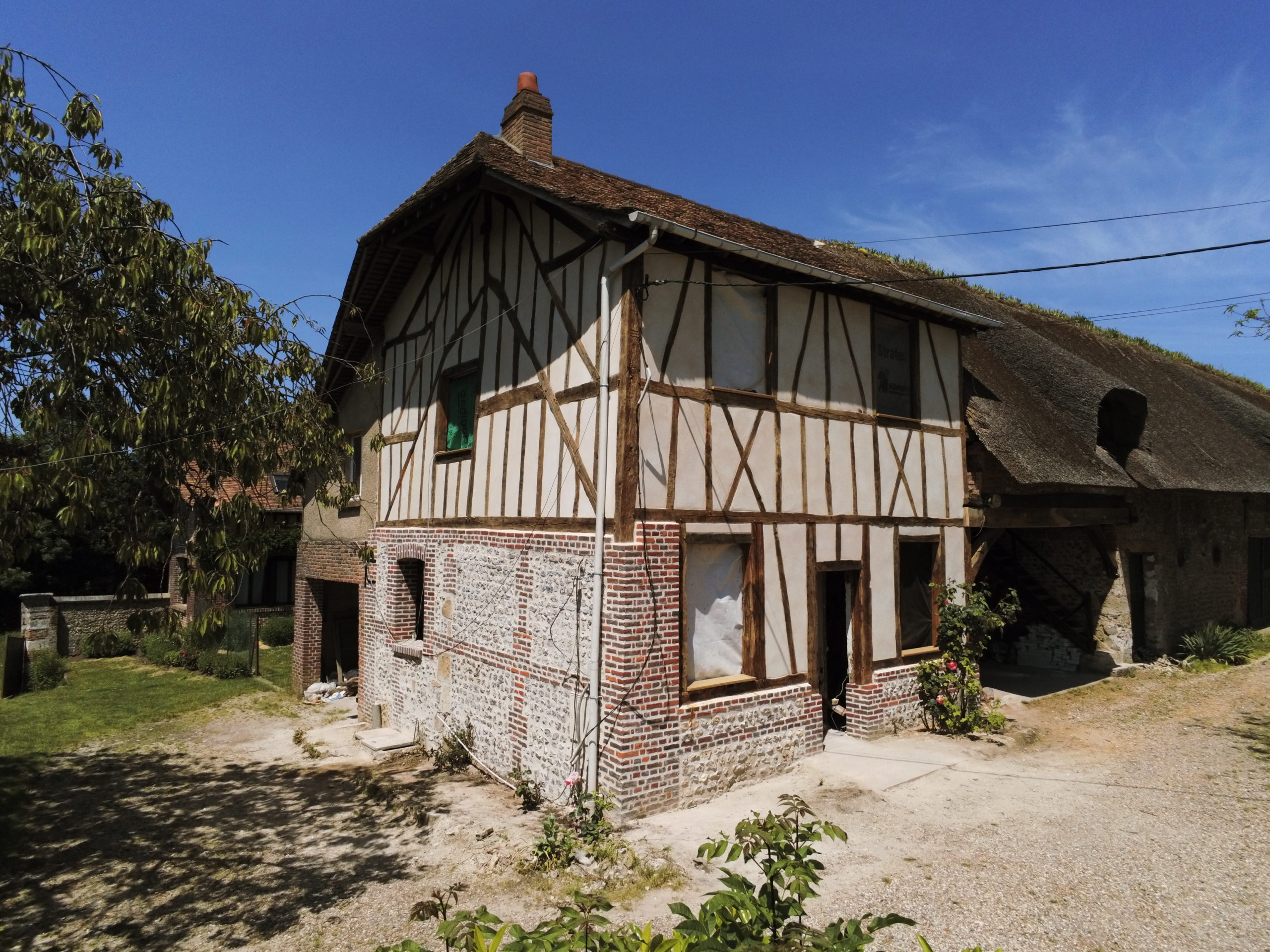 Charpente, colombages, enduits à la chaux, maçonnerie de briques et silex.